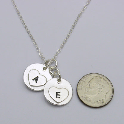 The back of the charms of the Circle Fingerprint with Birthstone Charm Necklace showing the small hearts engraved with initials