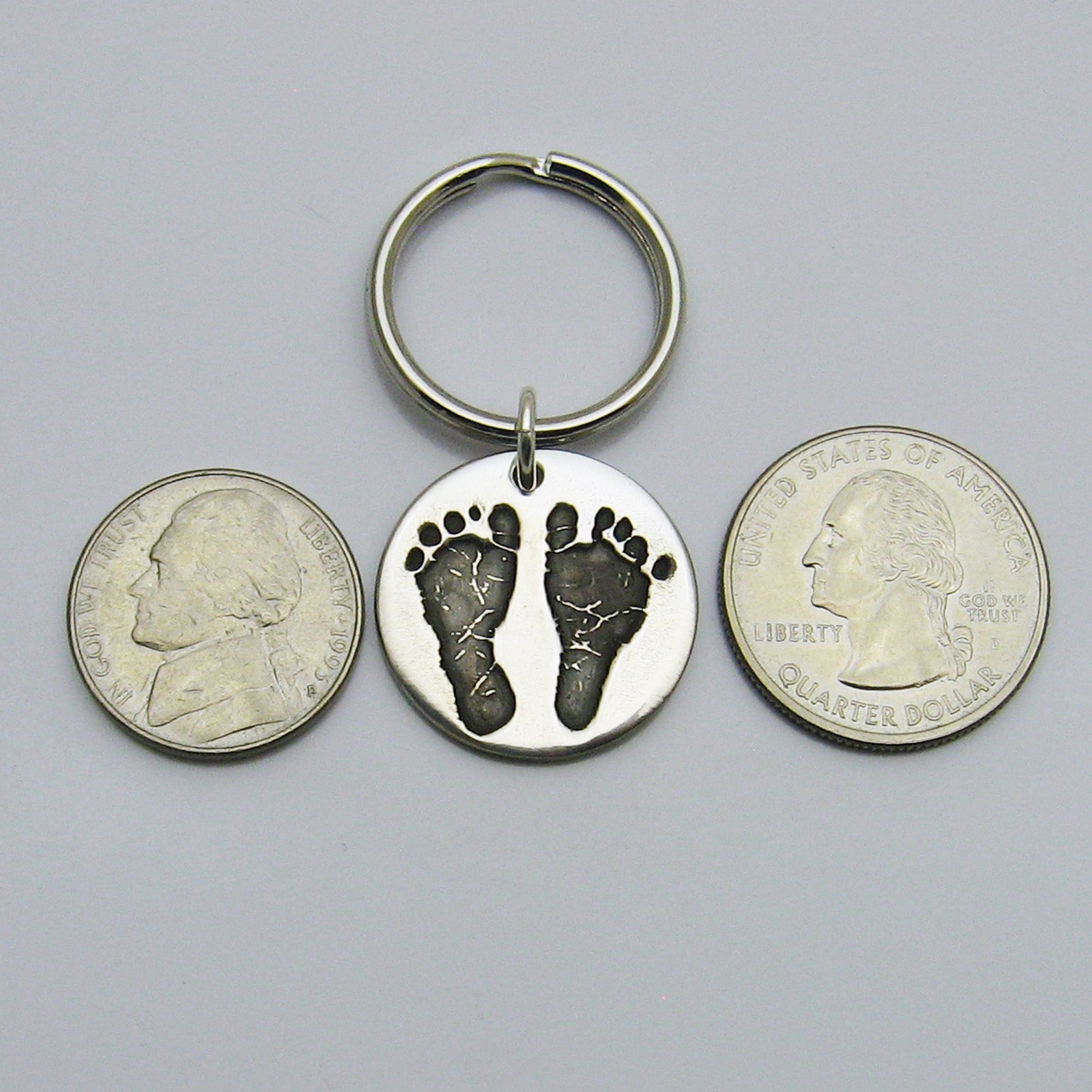 Circle Footprints Keychain next to nickel and quarter for size reference