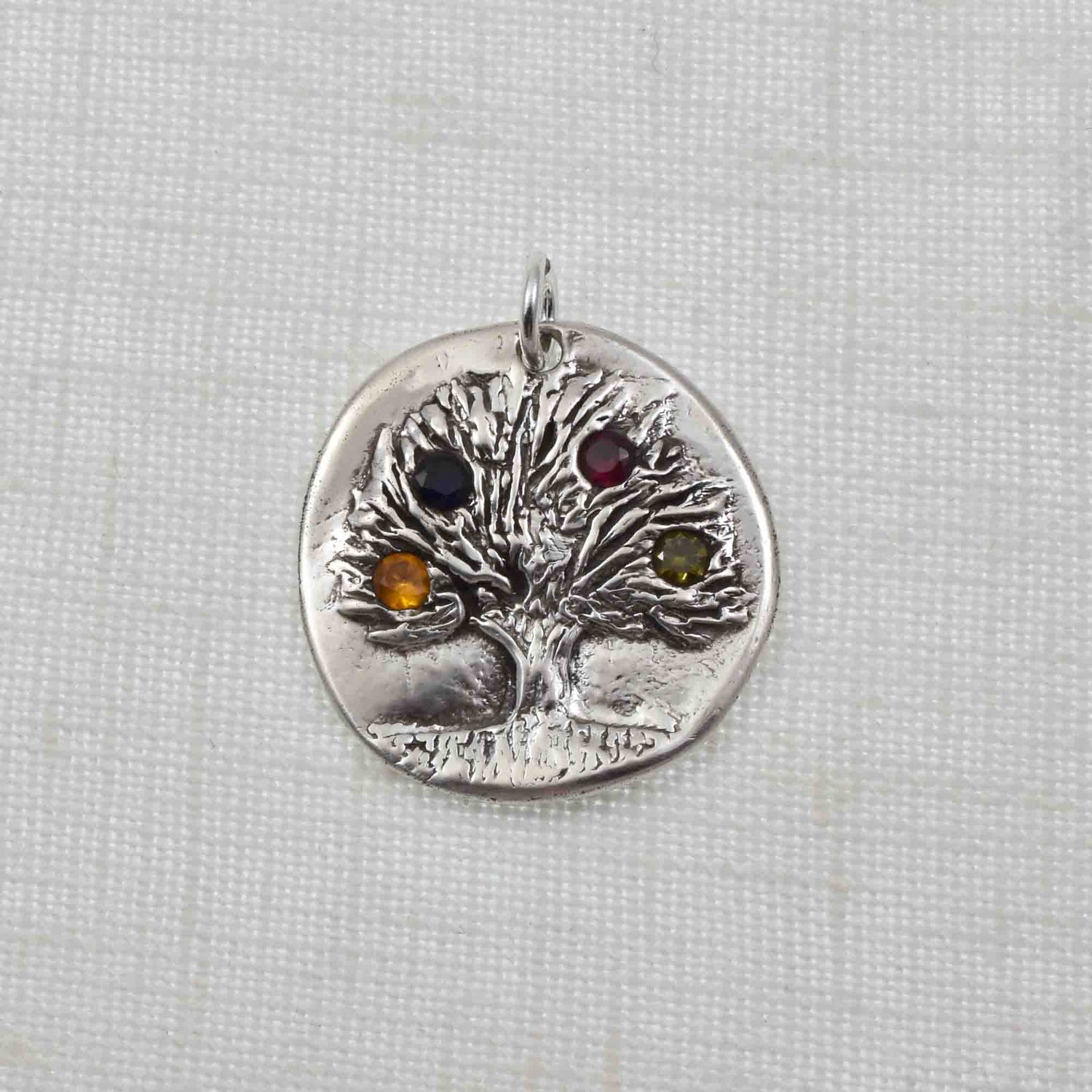 Silver birthstone tree necklace featuring 4 birthstones.  The pendant is embossed with a rustic tree design and birthstones are flush set into the tree branches.  