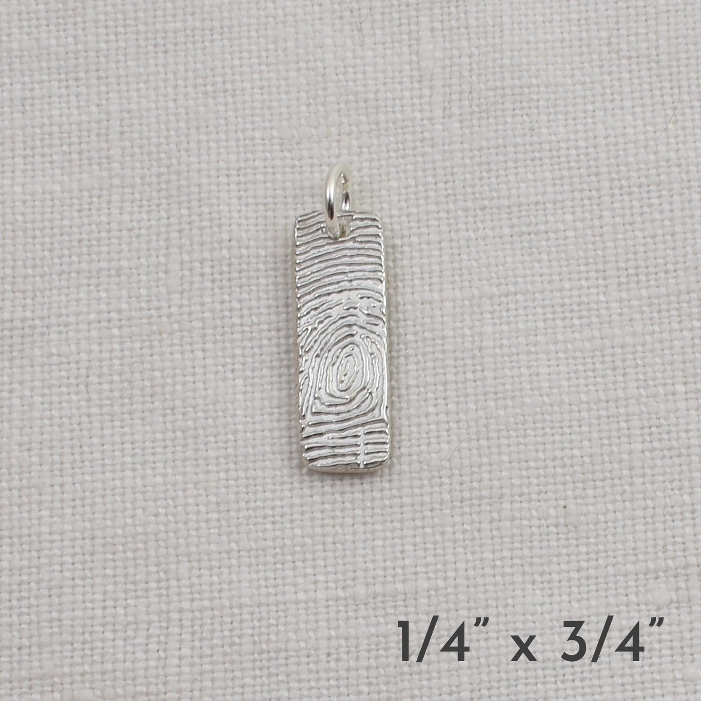 Silver pendant on a light beige fabric background with dimensions indicated.