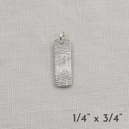 Silver pendant on a light beige fabric background with dimensions indicated.
