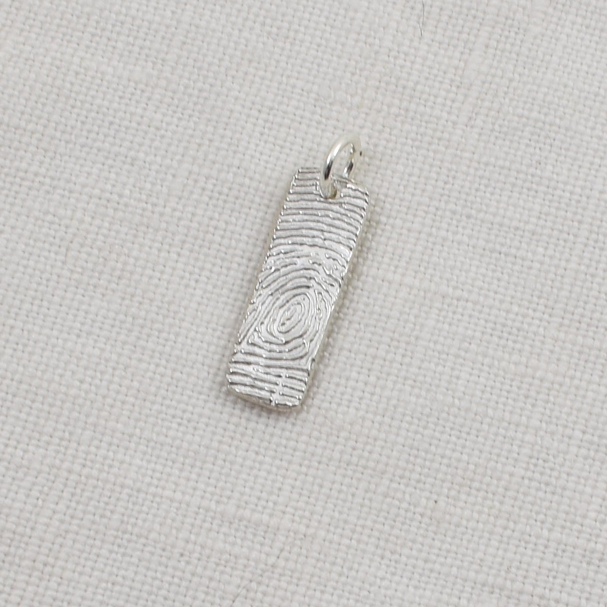 Silver fingerprint pendant on a light beige background