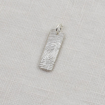 Silver fingerprint pendant on a light beige background