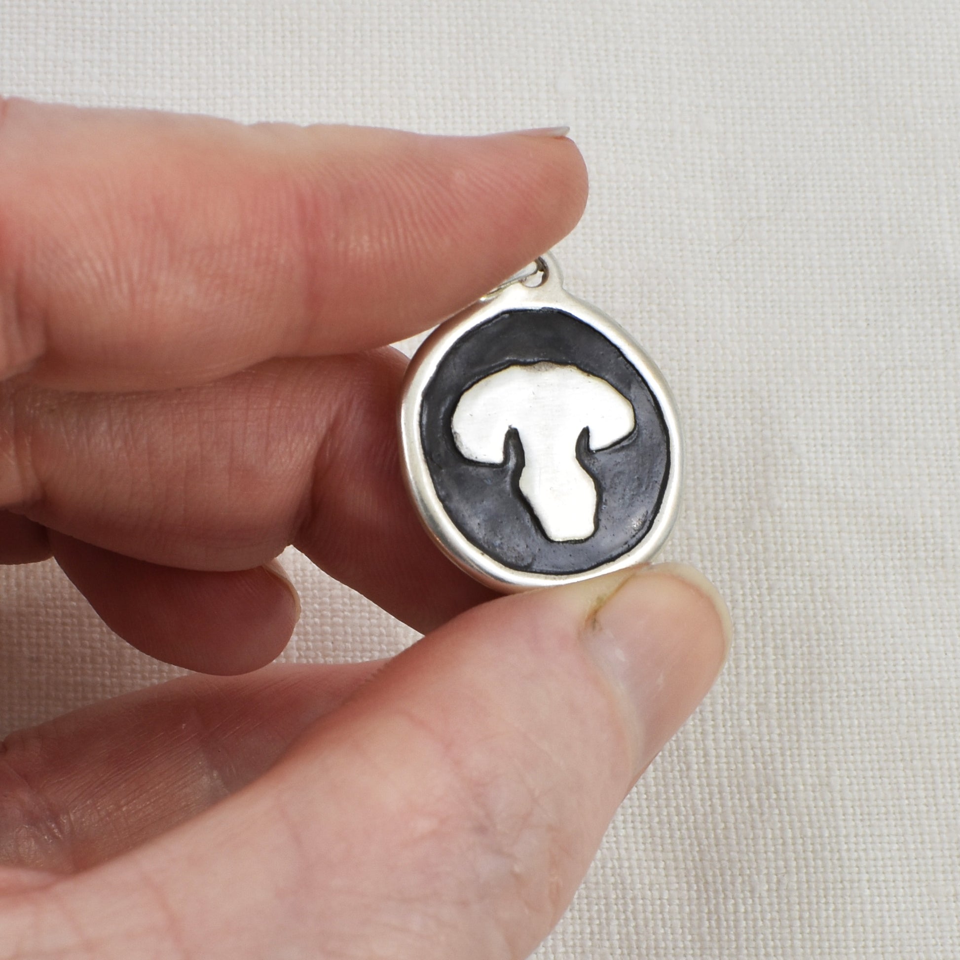 Dog Nose Embossed Circle Pendant, Necklace or Keychain Shown being held for size reference