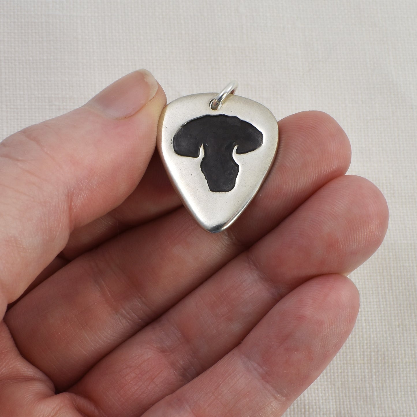 Dog Nose Guitar Pick Pendant Shown being Held for size reference