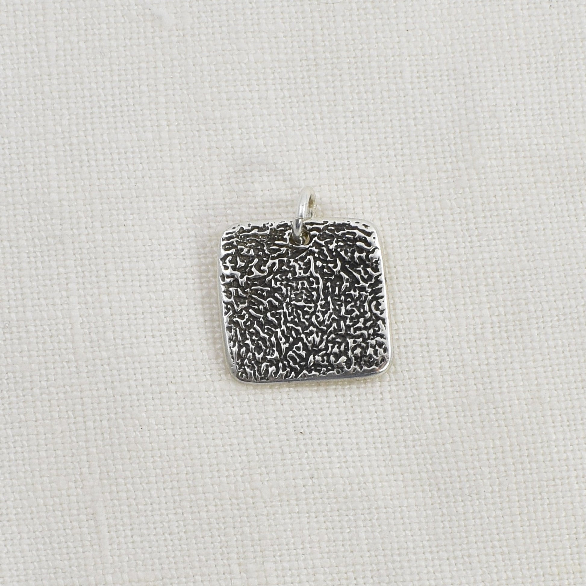 Dog Nose Textured Square Pendant shown as an example of a textured pendant with black patina