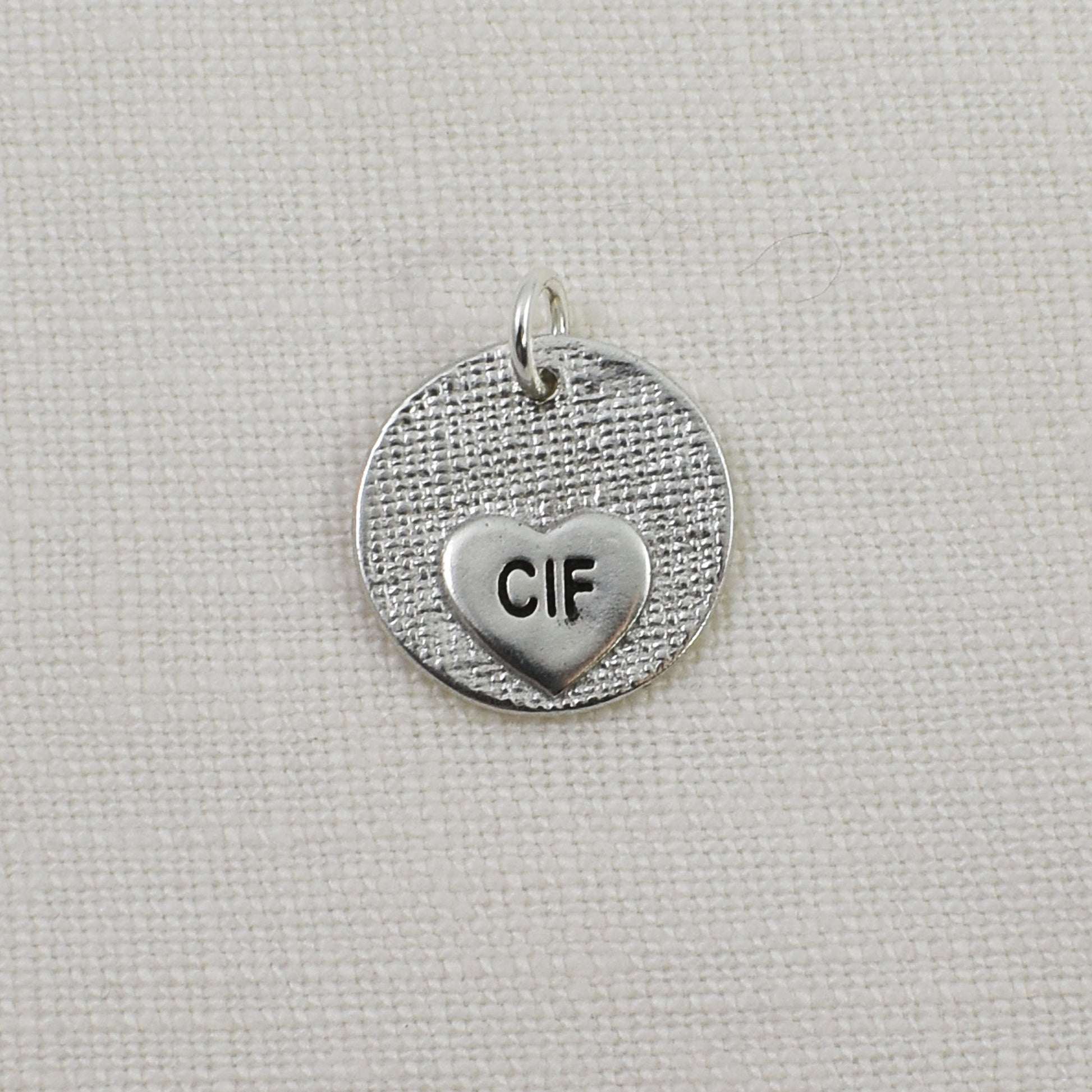 Back of circle with heart cutout fingerprint pendant showing small engraved heart