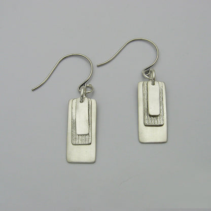 Silver Rectangle Earrings layered with graduating sizes.  The top and bottom layers are matte silver and the middle layer is textured silver.  