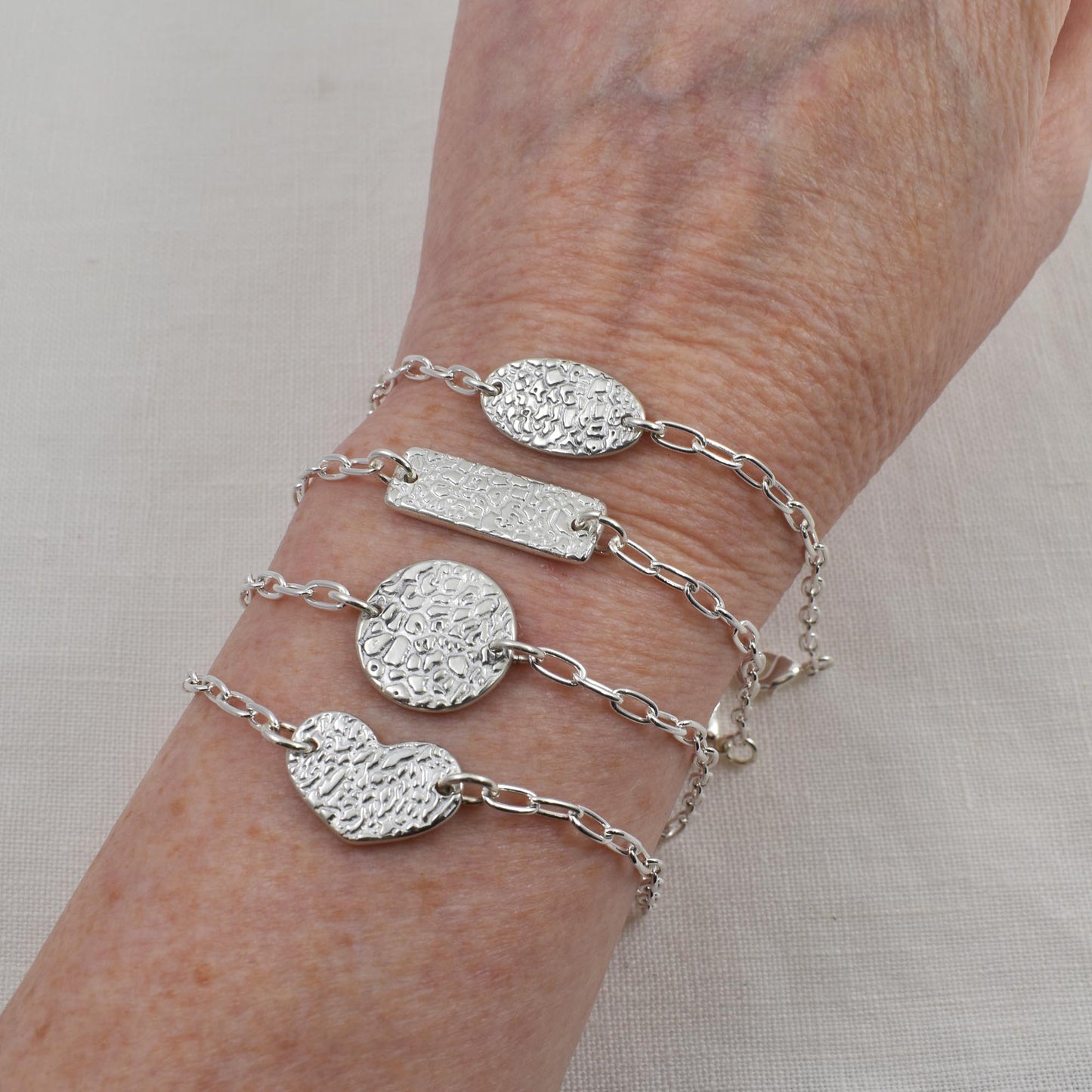 Dog Nose Texture Bracelet, Linked Memories Collection.  Bar, Circle, Heart and Oval Links are shown on wrist.  