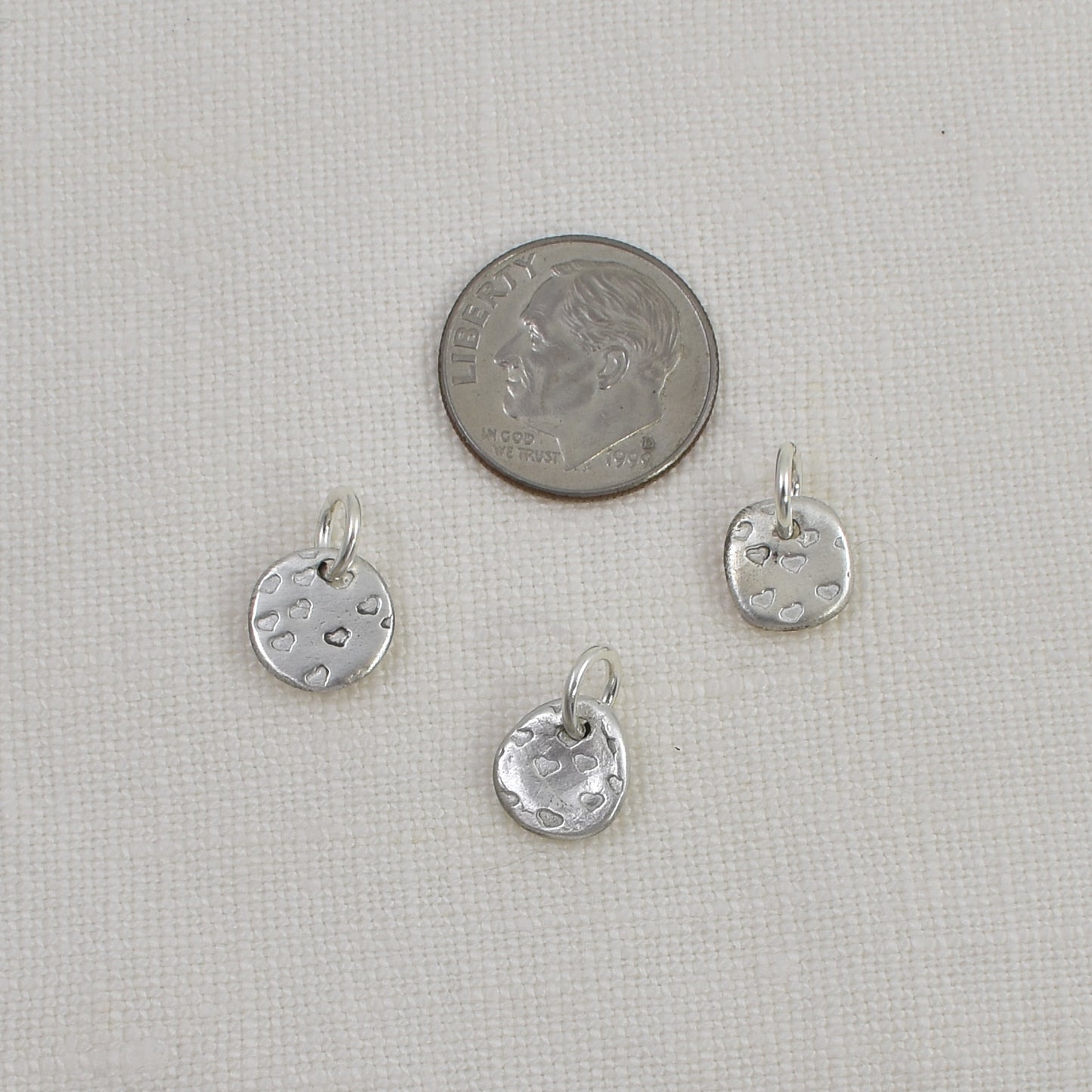 Back of 3 Tiny Sterling Silver Heart Charms shown next to a United State dime for size reference