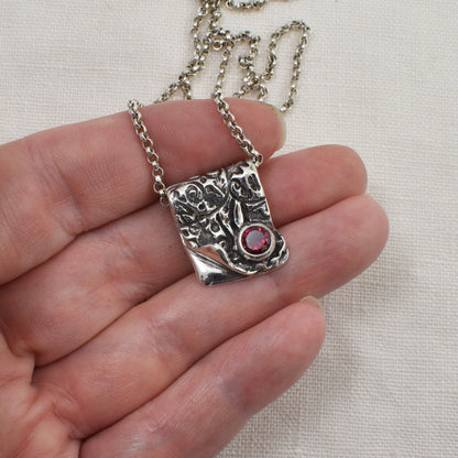 Silver and Ruby Cubic Zirconia Ember Fold Necklace shown on a hand for size reference