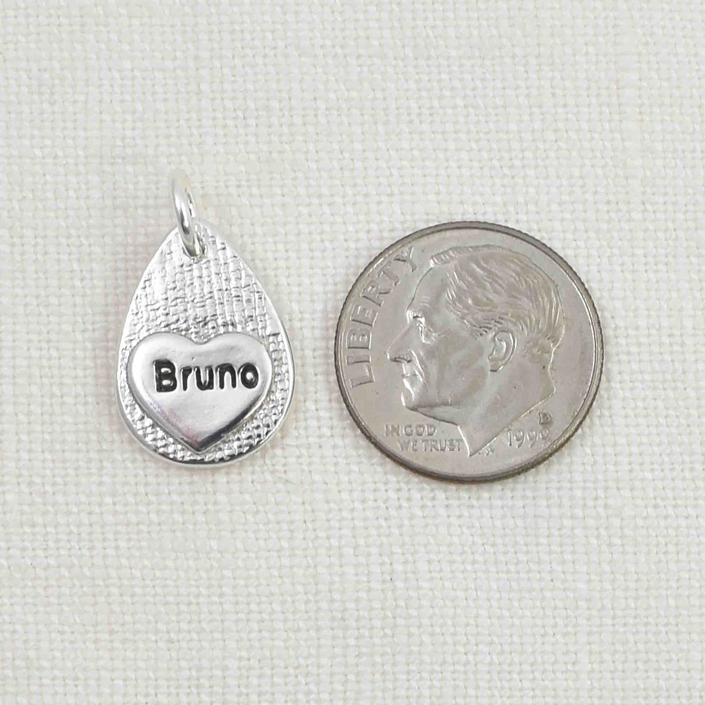 Back of Sterling Silver Cat Nose Textured Teardrop Pendant showing small engraved heart.  Shown next to a United States dime for size reference