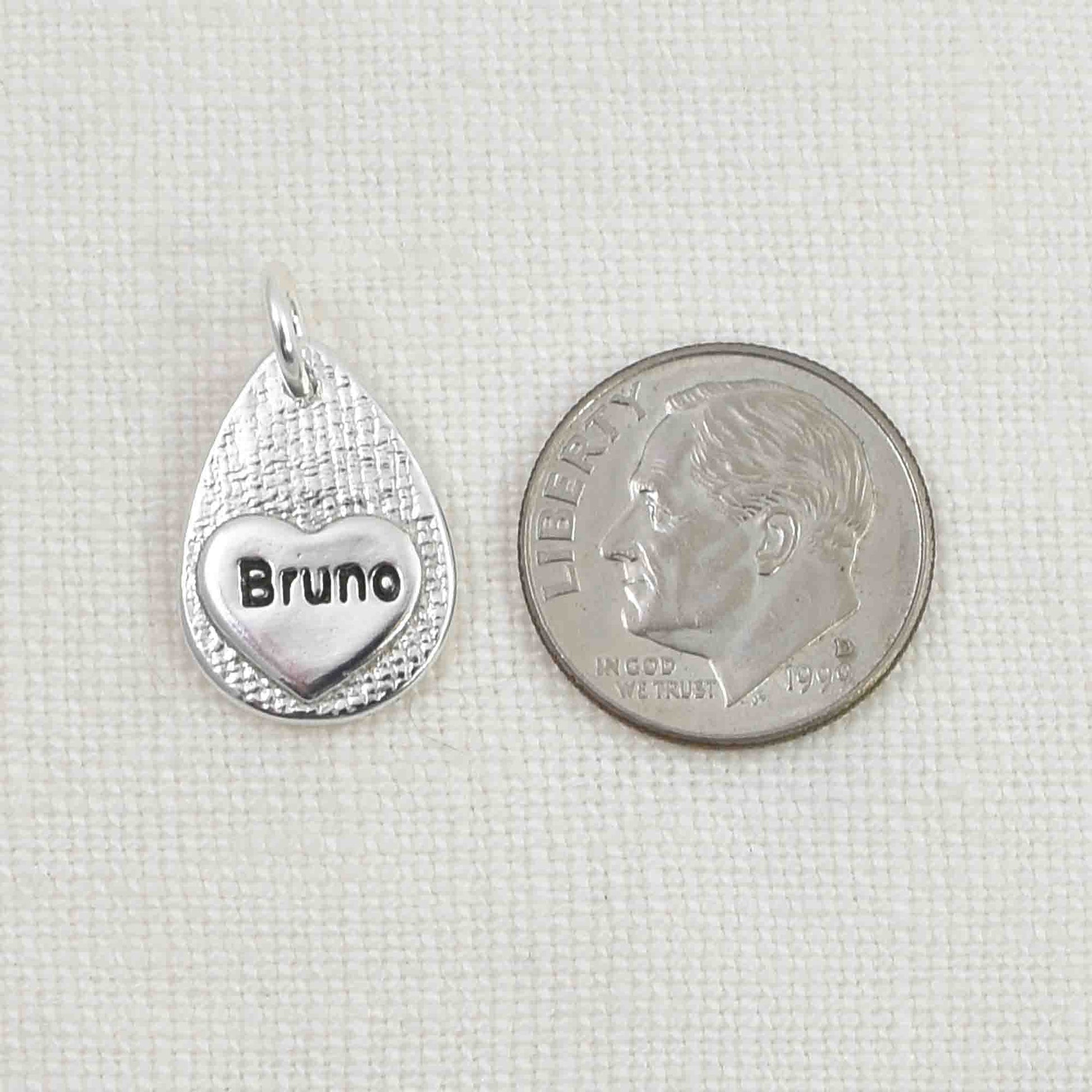 Back of Sterling Silver Cat Nose Textured Teardrop Pendant showing small engraved heart.  Shown next to a United States dime for size reference