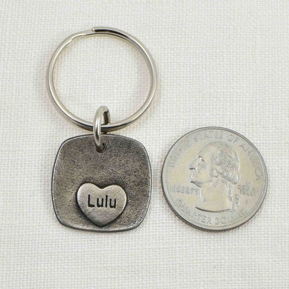 Back of Rustic Metal Dog Nose Square Keychain showing engraved heart.  Shown next to a United States quarter for size reference